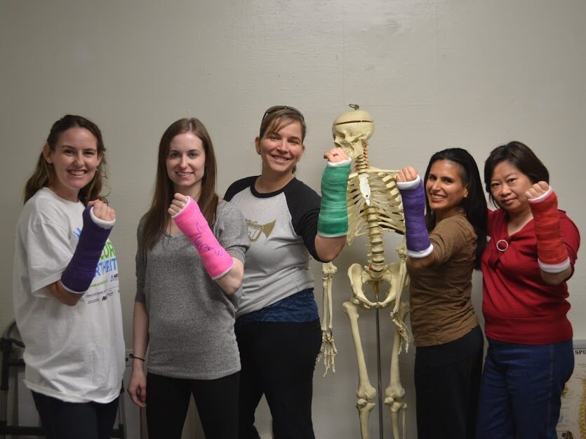 Five nurses hold up casts on their arms